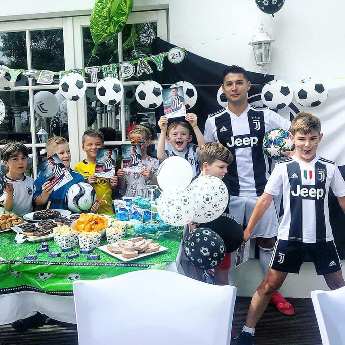 Fußball-Freestyler Saki verteilt Autogrammkarten beim Kindergeburtstag im Restaurant.