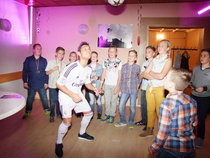 Indoor Fußball-Unterhaltung: Kinder erleben eine spektakuläre Jongleur-Show in der Halle.