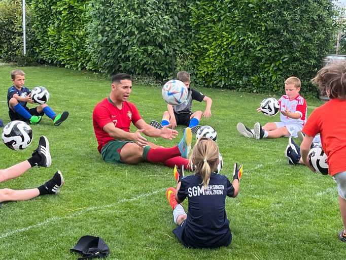 Fußball-Kindergeburtstag in Bayern: Kinder lernen im Garten neue Tricks vom Profi-Freestyler.