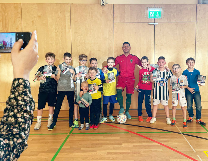 Gruppenfoto glücklicher Kinder nach der Fußball-Show in einer Turnhalle.