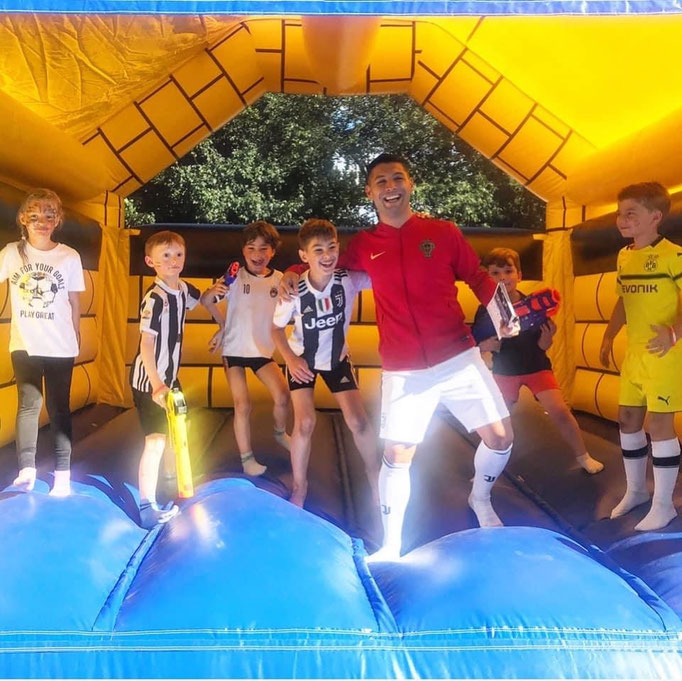 Fußball-Kindergeburtstag Pause: Kinder erholen sich bei der Hüpfburg vom Training.