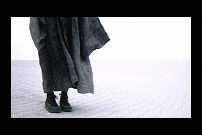 close up of torso and legs of person in a robe in the wind in the desert