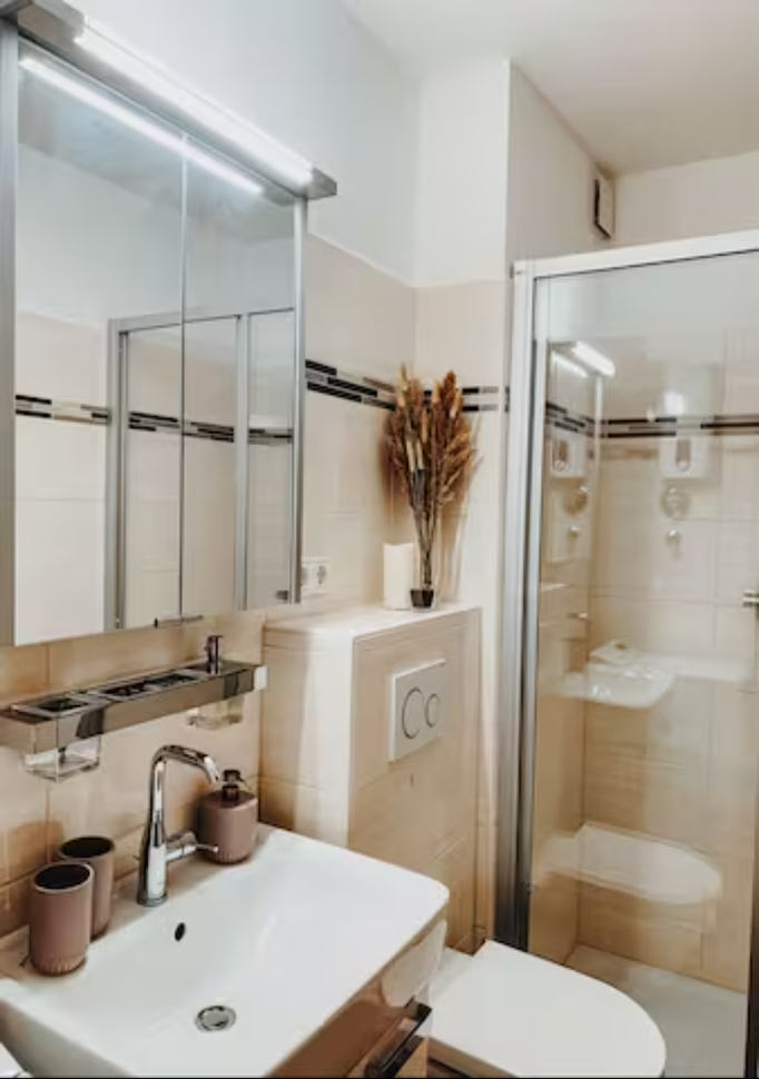 Modernes und gepflegtes Badezimmer in unserer Ferienwohnung in Winterberg-Niedersfeld. Ausgestattet mit Dusche, WC, Waschbecken und Spiegelschrank. Dezente Deko und warme Fliesen schaffen eine freundliche und einladende Atmosphäre.