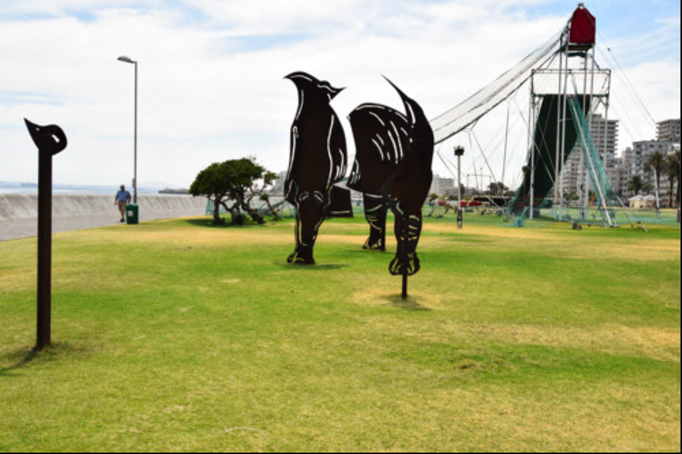2016 | Kapstadt | «Three Anchor Bay»: «Giganto-Eisenplastik». Durch ein Guckloch gesehen ergeben die 5 «Einzelteile» ein riesengrosses Nashorn. Eine Super-Idee!