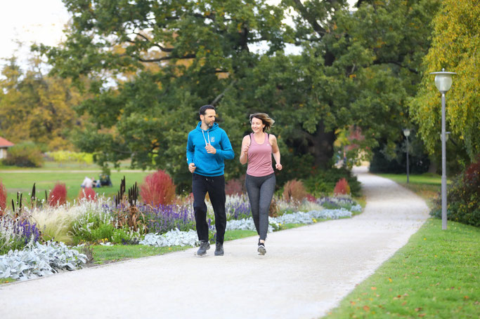 Mann und Frau joggen im Park nebeneinander