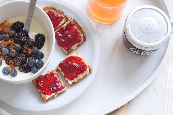 Gemütliches Frühstück im Bett mit Joghurt, Obst, Smoothie, Saft und Marmeladenbrot von Glück Marmelade.