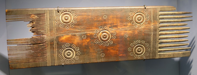 Comb, wood, 4th - 7th c., Hessisches Landesmuseum, Darmstadt. Photo: Epochs of Fashion. A rectangular wooden comb with the teeth on either end, with circular engravings