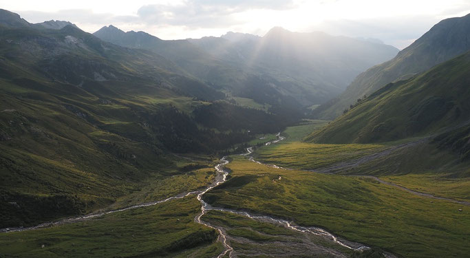 Aussicht von der Hütte in der Abendstimmung nach dem Regen, die Bäche glitzern im Tal von der Sonne.