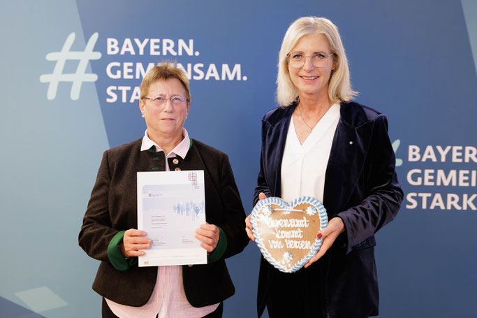 Bayerns Sozialministerin Ulrike Scharf (re.) überreicht den Ehrenamtsnachweis Bayern an KDFB-Frau Hildegard Lutz. Bildnachweis: Schäffler/StMAS