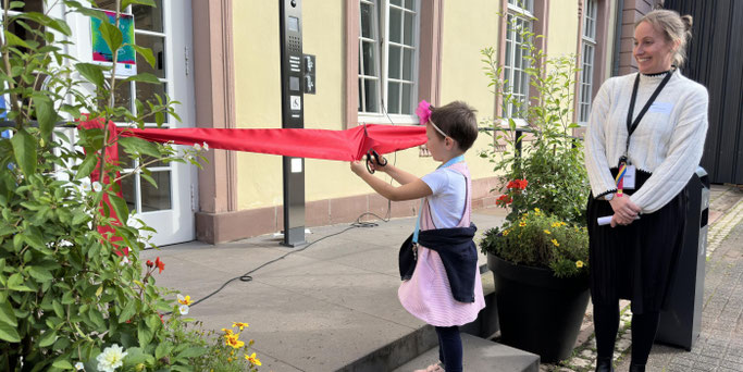 Klara durchschneidet das Eröffnungsband, daneben Jacqueline Maron © Inge Hülpes/Bistum Trier