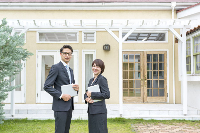 新築住宅の前でほほ笑む根本建材スタッフ