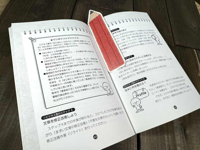 「赤い鉛筆型のしおり」を本に挟み込んだ写真。楽しいしおりなので、読書が楽しくなります。