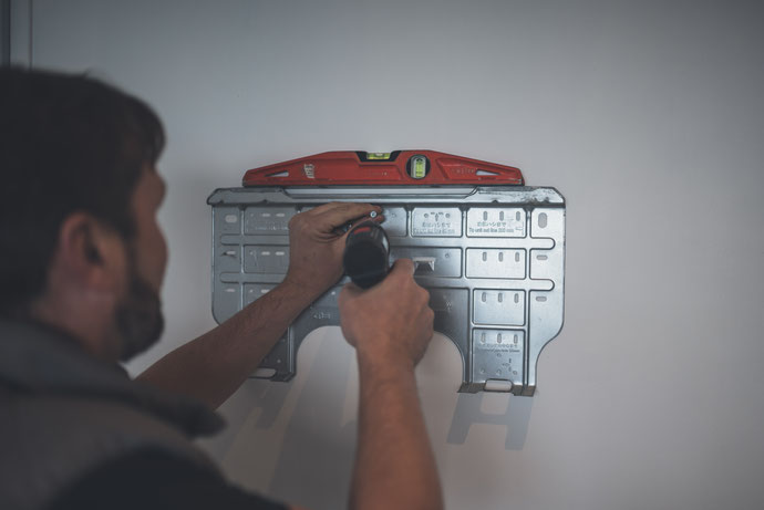 Installateur Clim Alpes fixant la platine murale d'une climatisation en Isère