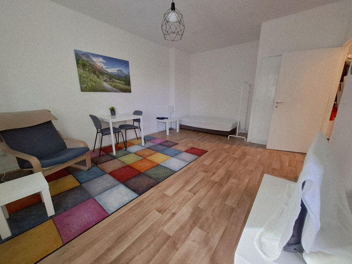 Minimalistischer Wohnraum mit hellem Holzboden und buntem Teppich als Rückzugsort für mehr innere Ruhe