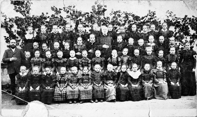 Foto der Mädchenklasse, links: Lehrer Franz Luhmann, rechts: Lehrerin Anna Kalthoff, mittendrin: Pastor Mönnigs