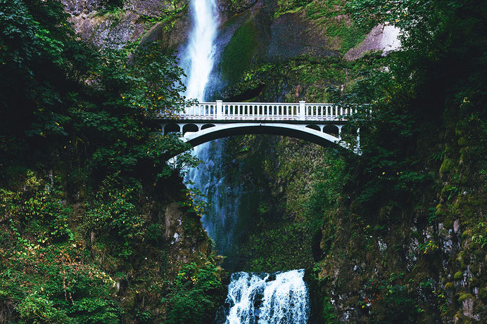 Eine Brücke in den Bergen vor einem Wasserfall sinnbildlich dafür konstruktive Lösungen in Konflikten zu finden