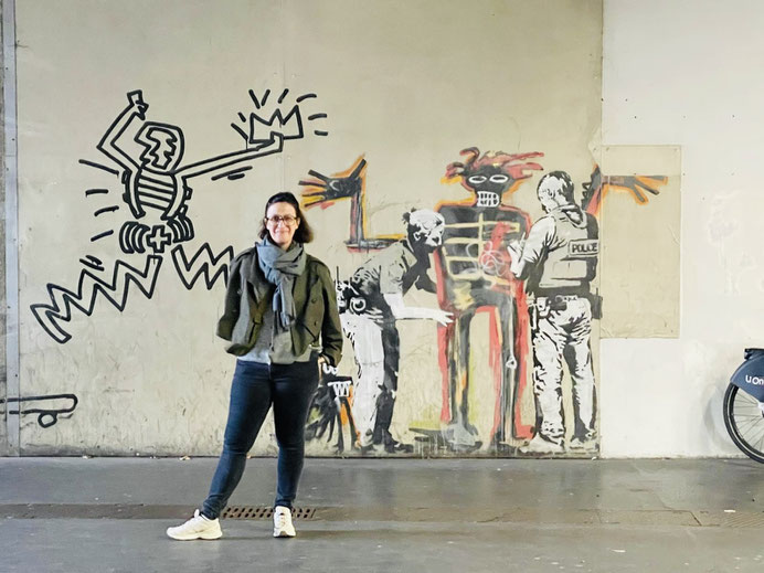 Eine Unterführung mit einem Graffiti von Banksy, davor stehe eine Frau