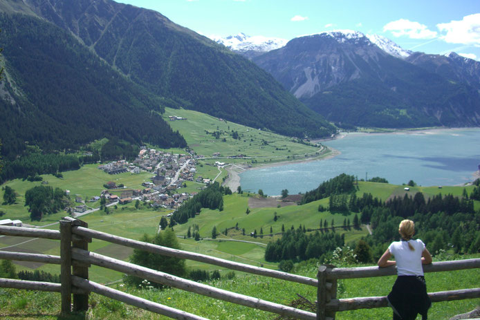 Ausblick Richtung Reschen am Reschenpass im Vinschgau: tief blau der Reschensee mit dem versunkenen Dorf Reschen