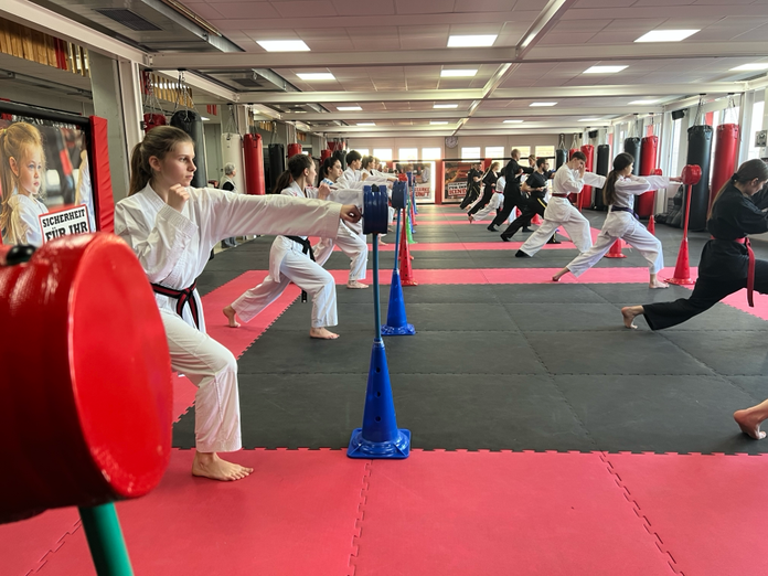 Mehrere Kinder üben eine Karate Technik.