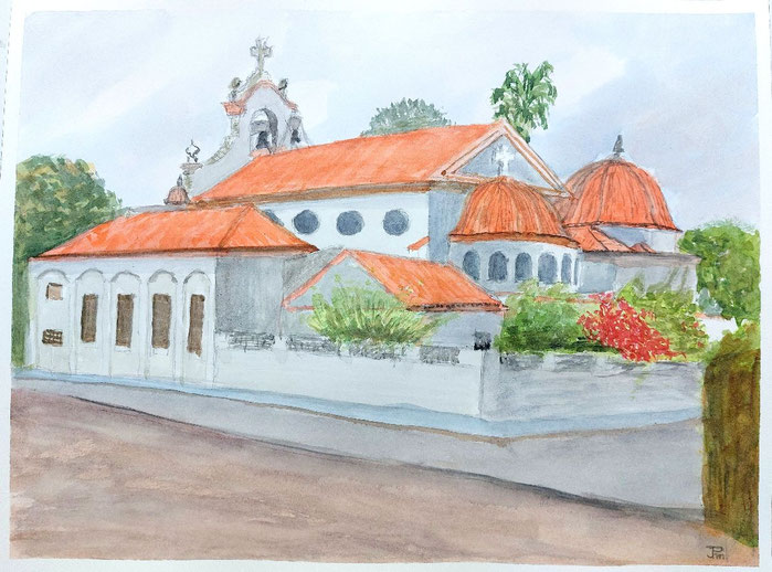 Iglesia de María Inmaculada de Vera con cúpulas rojizas, campanario y vegetación en un día nublado.