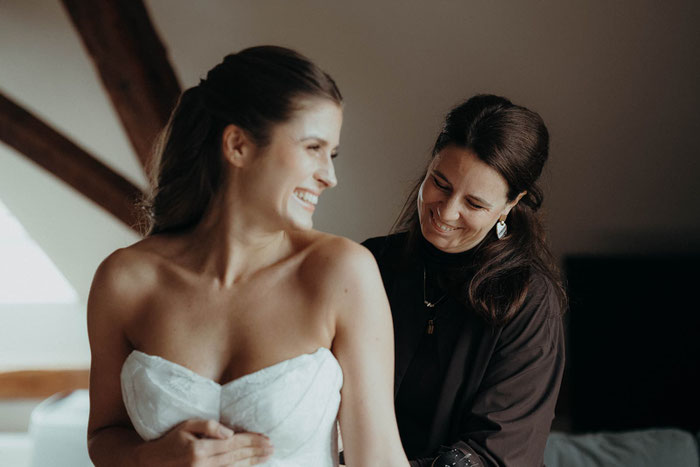 Designerin mit Braut in ihrem Atelier und Schneiderei beim anfertigen eine maßgeschneiderten Brautkleides
