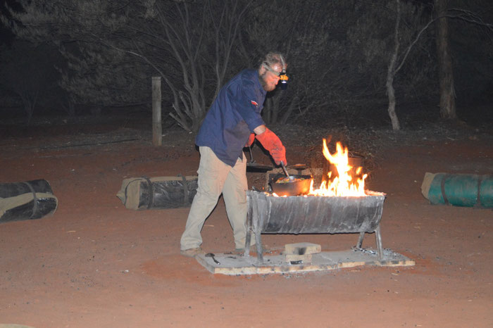 Unser Guide Nacho zaubert ein Abendessen über dem Lagerfeuer. Rundherum die noch zusammengerollten Swags.