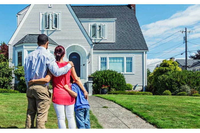 Family standing arm in arm viewing front of new home after home inspection