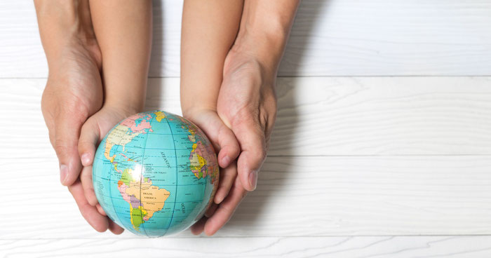 Parent and child's hands holding a small globe