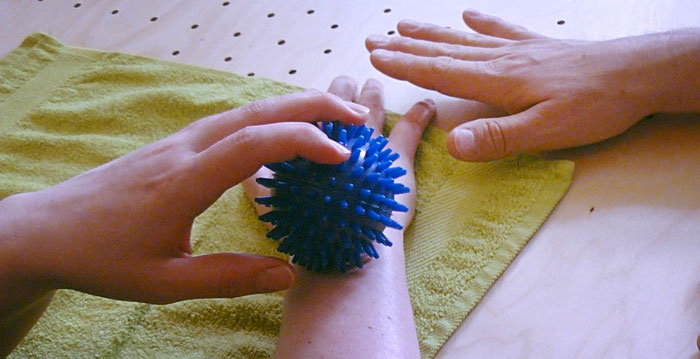 Patientin trainiert Sensibilität ihres Unterarms mit einem Igelball