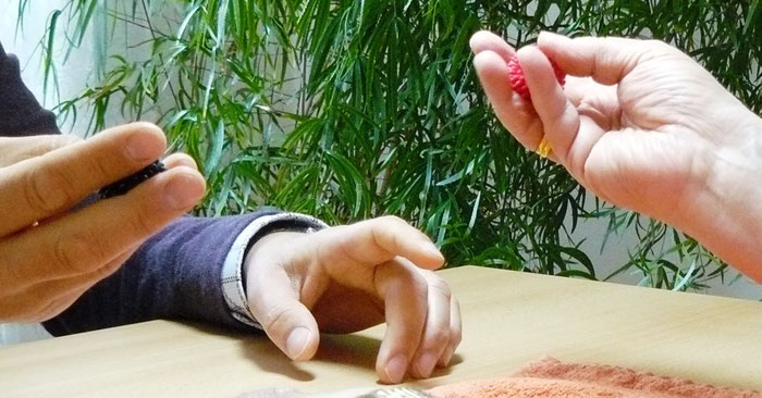 Therapeut zeigt Patientin Feinmotorik-Übung für die Finger mit einem Mini-Igelball