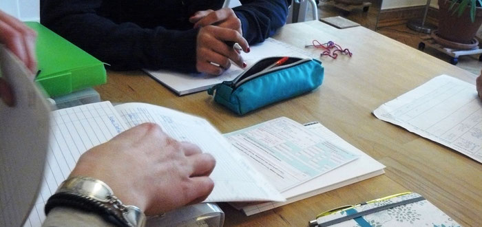 Team bespricht Patient*innen. Vor ihnen auf dem Tisch liegen Akten und Verordnungen.