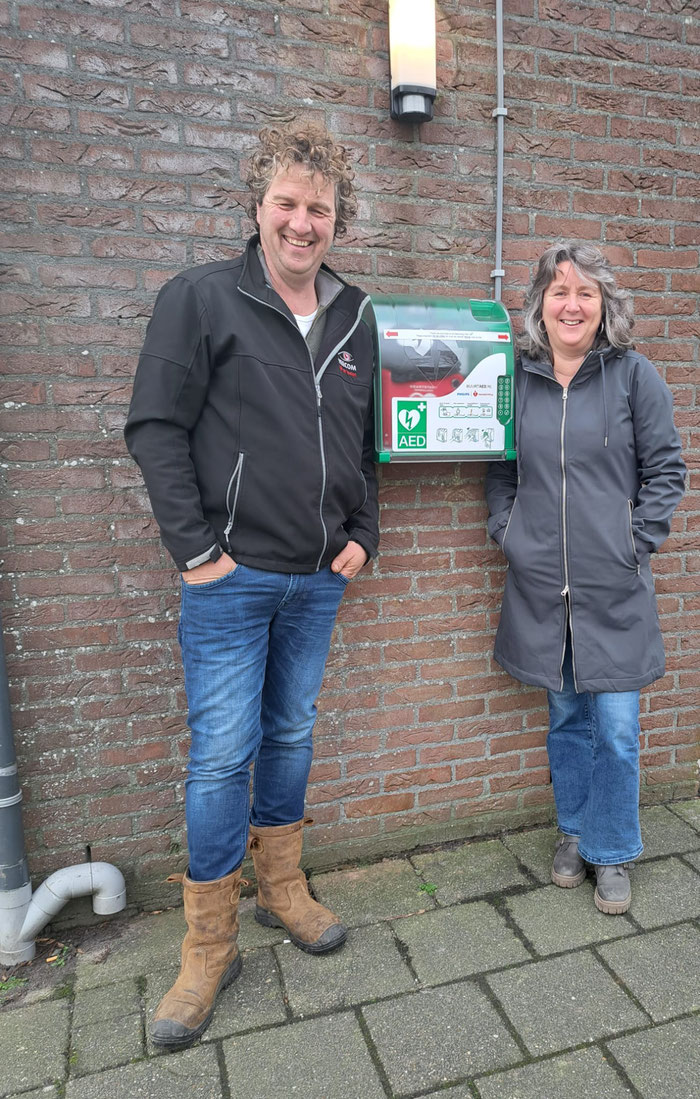 Johan van der Kooi (voorzitter dorpshuis) en Betty van der Veen (voorzitter dorpsbelang) bij de AED in Raard