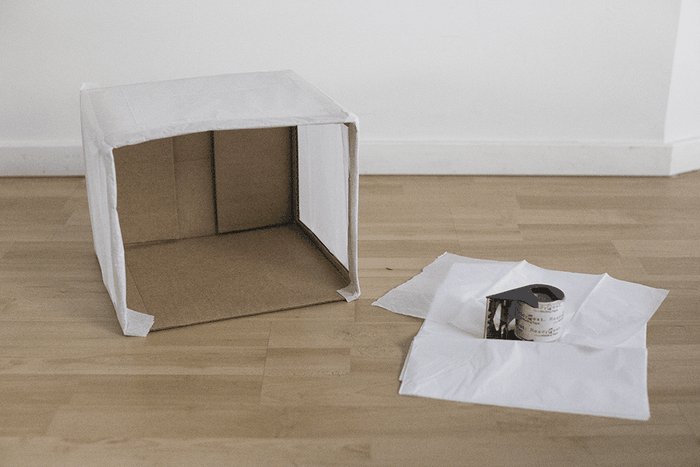 Carton recouvert de papier de soie sur trois côtés, scotch et papier de soie à droite sur le sol