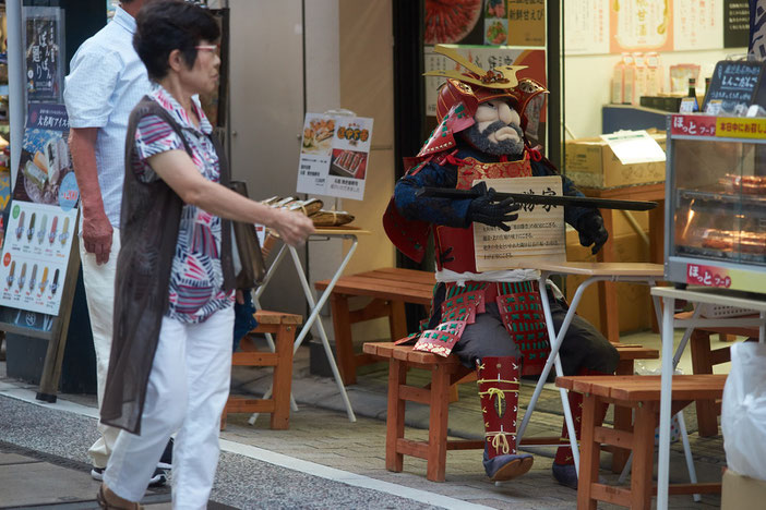 商店街の店舗の前、買い物をする年配の女性