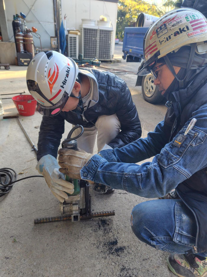 職人と一緒に鉄筋の切断をする生徒