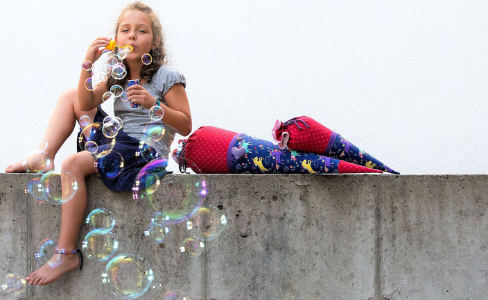 Bild: Mädchen auf Mauer mit Einhörnchen Schultüte und Seifenblasen