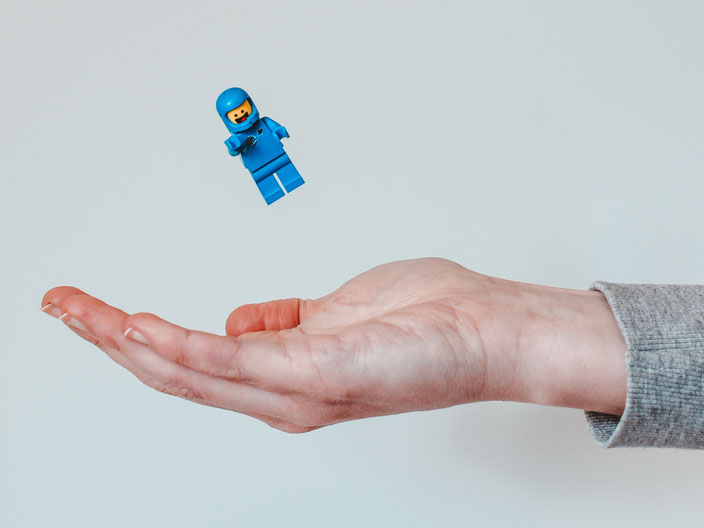 Ausgestreckte Hand fängt Legomännchen auf