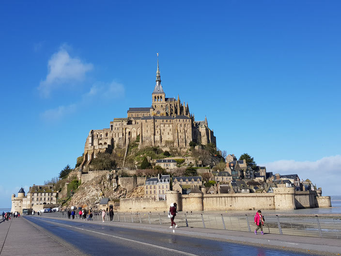 Le Mont Saint-Michel entouré de la baie, accessible via une passerelle