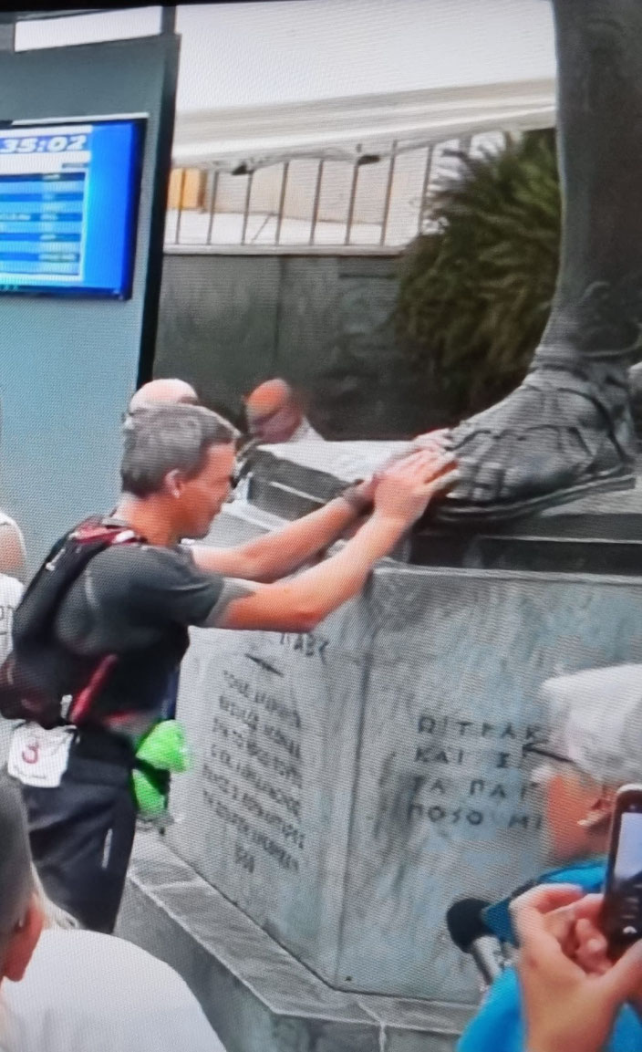 Harry Lange berührt in Sparta den Fuß von König Leonidas im Ziel des Spartathlon 2025 nach 246km in 35h26min Nonstop!