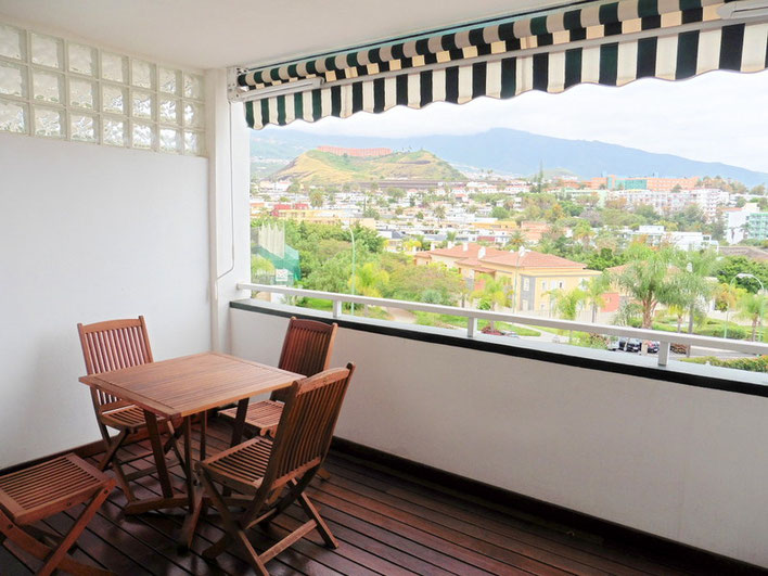 Ausblick vom Balkon mit Holzmöbel auf das Umland der Wohnanlage