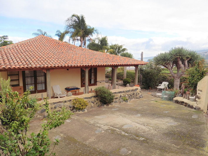 Sicht von der Finca auf das Haus und im Hintergrund sind Palmen und das Meer zu sehen.