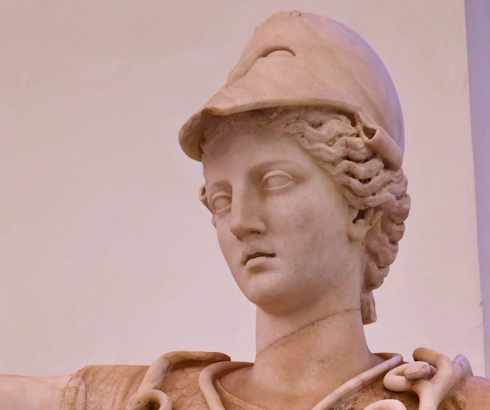 Marble statue of a woman wearing a crested helmet and armor, with wavy hair and a calm, focused expression.