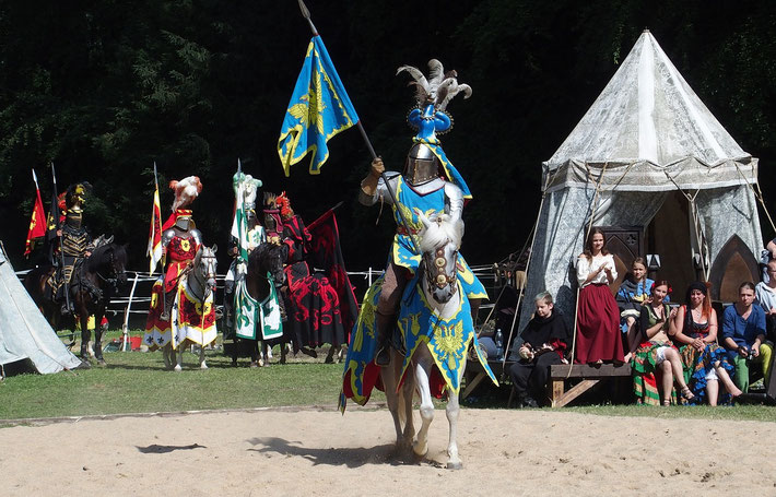 A medieval jousting tournament with knights in colorful armor on horseback.