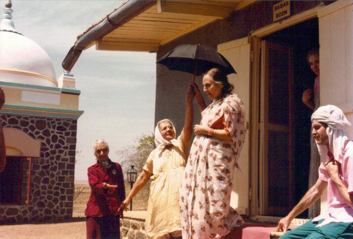 Theus (far right) sitting outside Baba's Cabin in Upper Meherabad with Mehera & Mani coming out of the cabin.