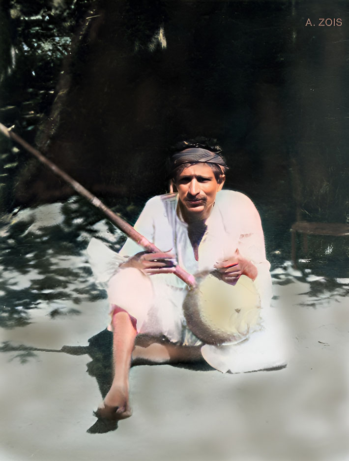 66. 1922 : Poona, India. Meher Baba playing an Indian instrument outside his thatched hut. 