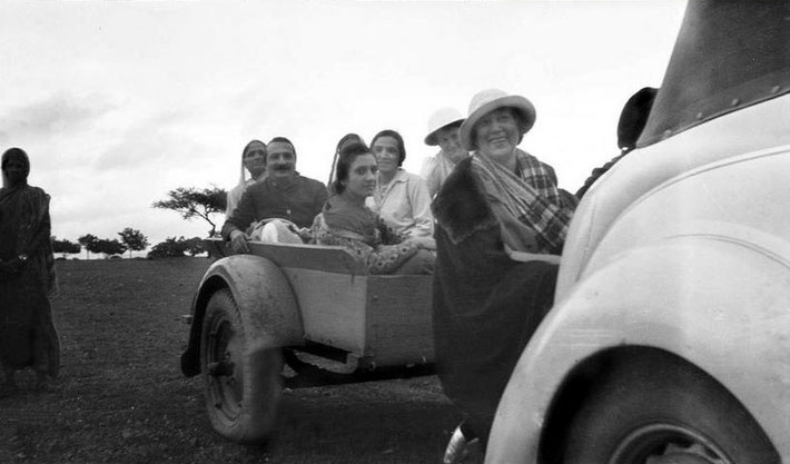 1935 Ford 4-door Auburn Deluxe Convertable Sedan with ( dickie ) rumble seat and luggage rack, which Nadine is sitting on and pulling a trailer with Baba and women.