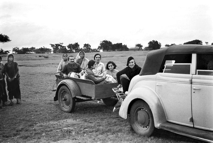 Late 1930s - near Ahmednagar's Tower of Silence. Norina riding on Elizabeth's Ford V8 4-door convertable' s "Dickie" seat. Baba and his women Mandali are riding on the trailer. Courtesy of MN Publ.