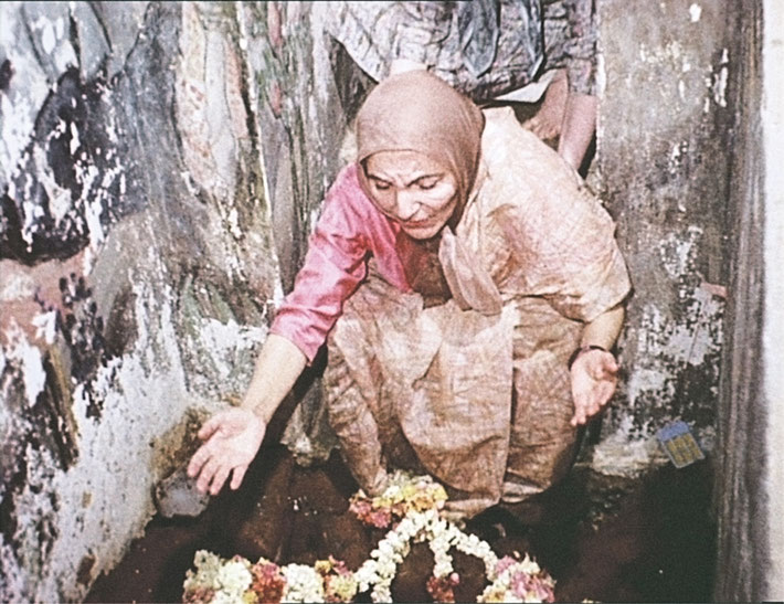 Mehera laying flowers at his feet. Still from a film by Vinod Shah.