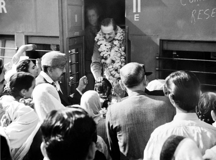 India ; Irene standing beside Meher Baba whilst on a train trip. Baba is blessing a female follower. Courtesy of MN Publ.