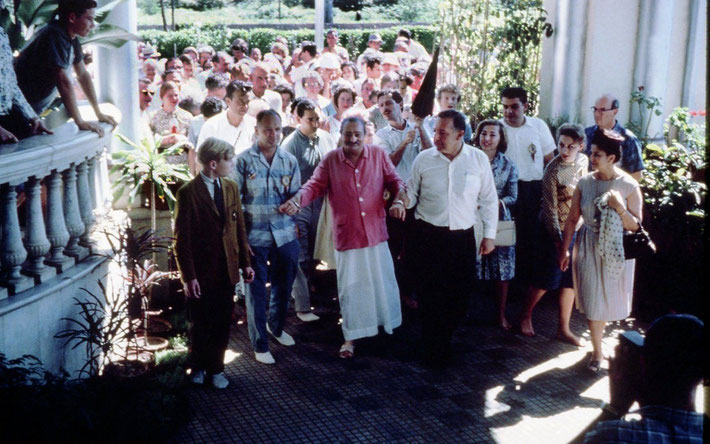 East-West Gathering - Charles Haynes in brown jacket left of Meher Baba, Lud Dimpfl assisting, Anita De Caro-Vieillard on the far right, Henry Kashouty behind Baba and Meherwan Jessawala holding umbrella ; Photo courtesy of Charles Haynes